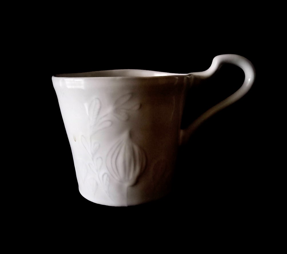 ヨーロッパのアンティークのようなマグカップ。ユニークな形の持ち手、表面の植物のレリーフが魅力です。